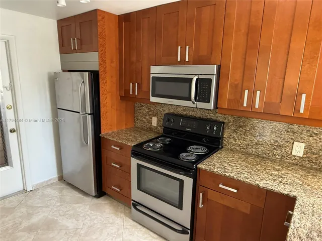 a kitchen with granite countertop wooden cabinets and stainless steel appliances