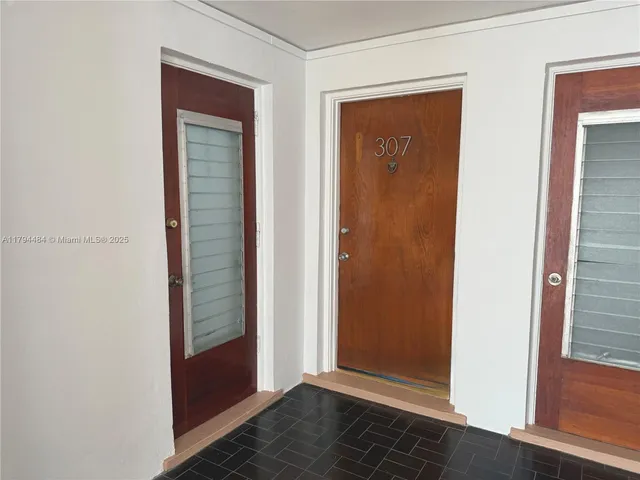 an empty room with wooden floor closet and windows