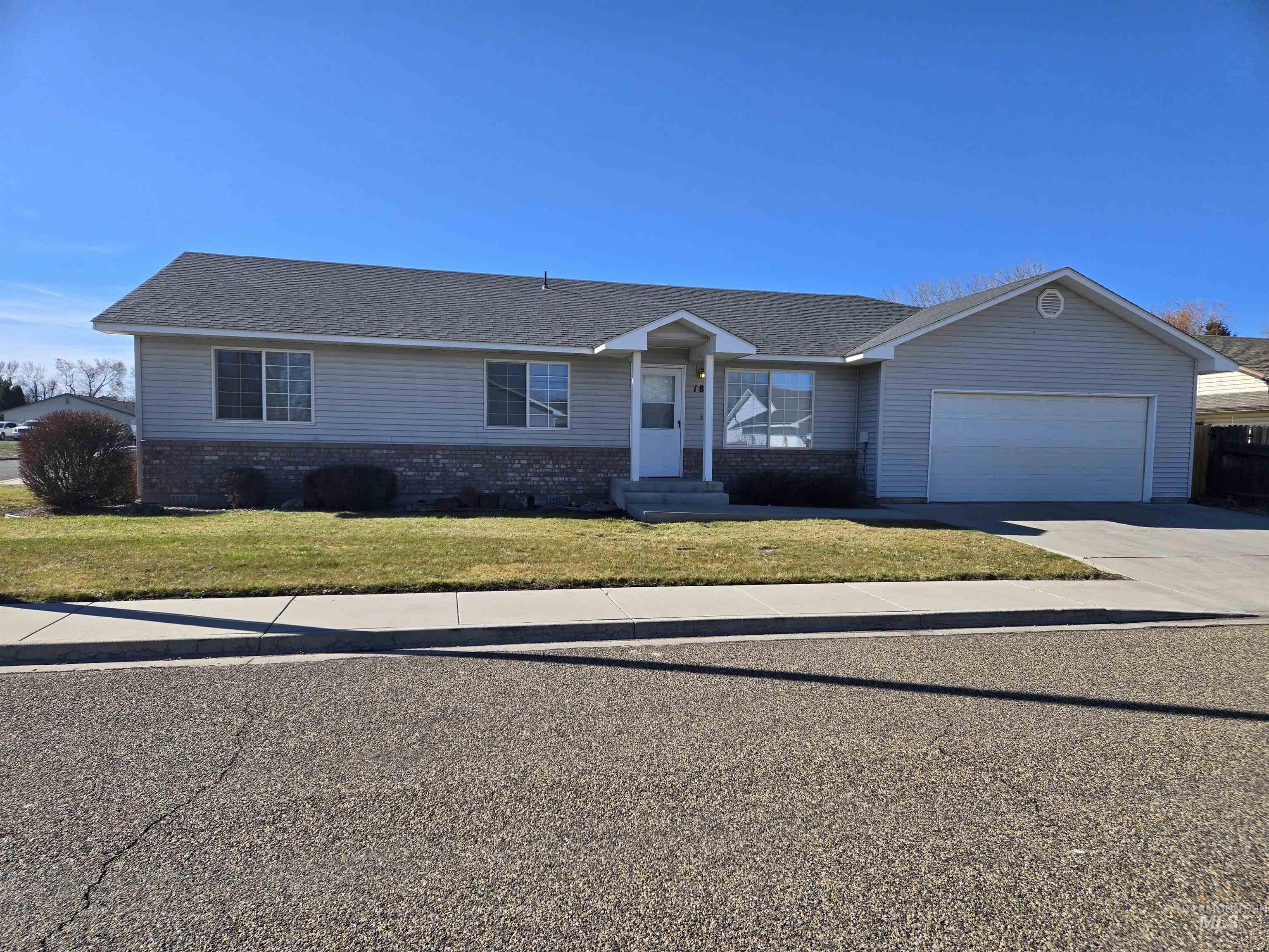 Ranch-style home featuring driveway, a front lawn, an attached garage, and brick siding