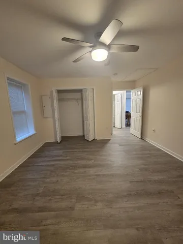 an empty room with wooden floor ceiling fan and windows