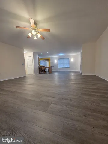 a view of an empty room with wooden floor and a ceiling fan