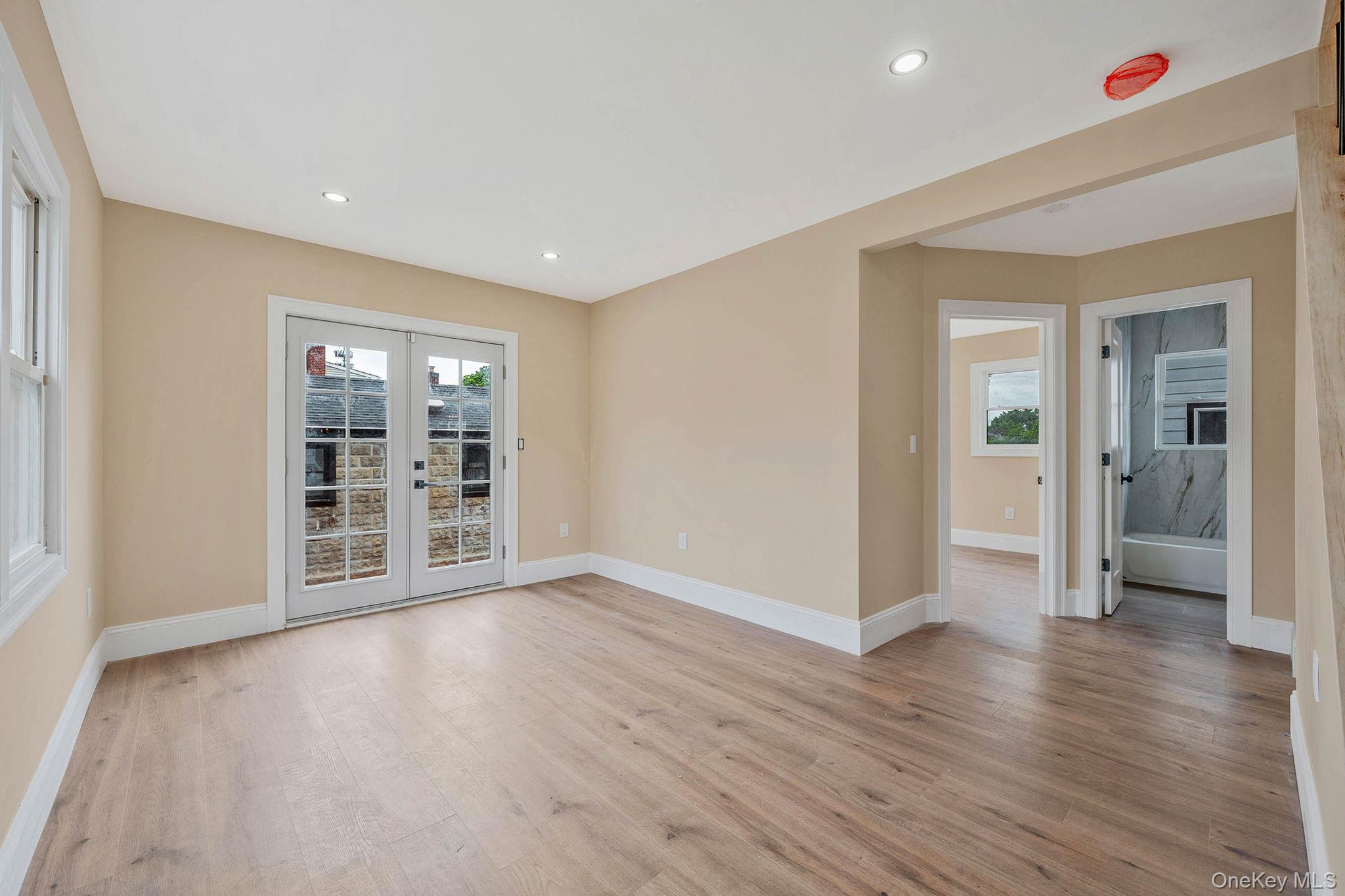 87 Sobro Avenue Valley Stream, NY 11580 - Photo 11 of 20 a view of an empty room with wooden floor and a window