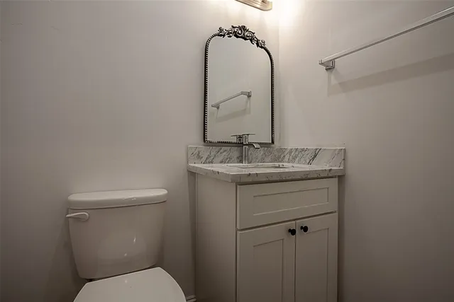 a bathroom with a granite countertop toilet sink and mirror