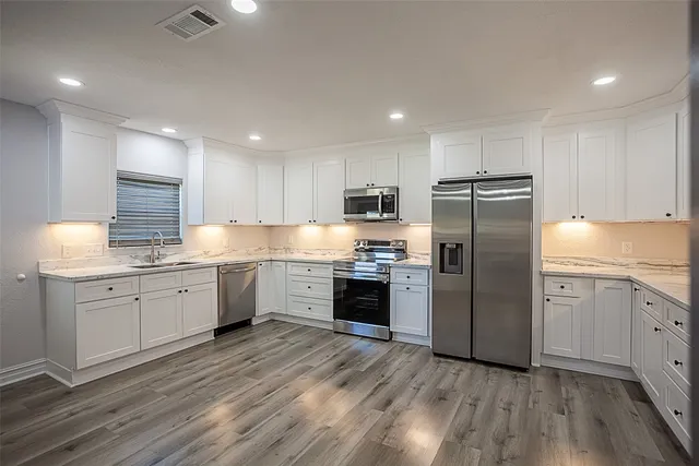 a kitchen with a refrigerator sink and cabinets