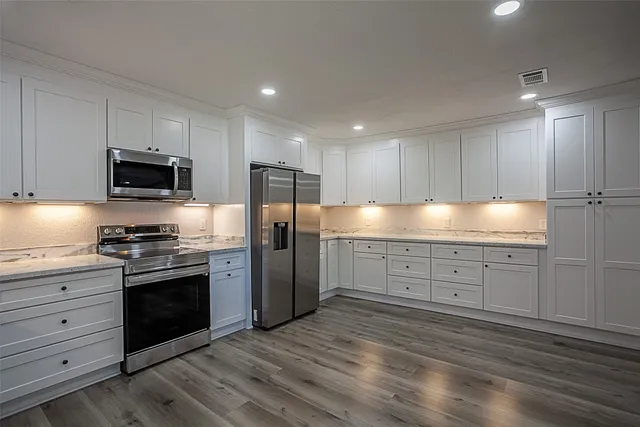 a kitchen with granite countertop white cabinets and stainless steel appliances