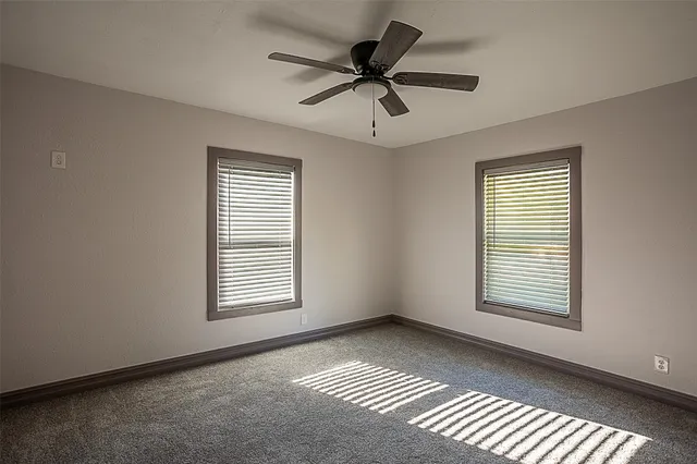 a view of an empty room with a window and a ceiling fan
