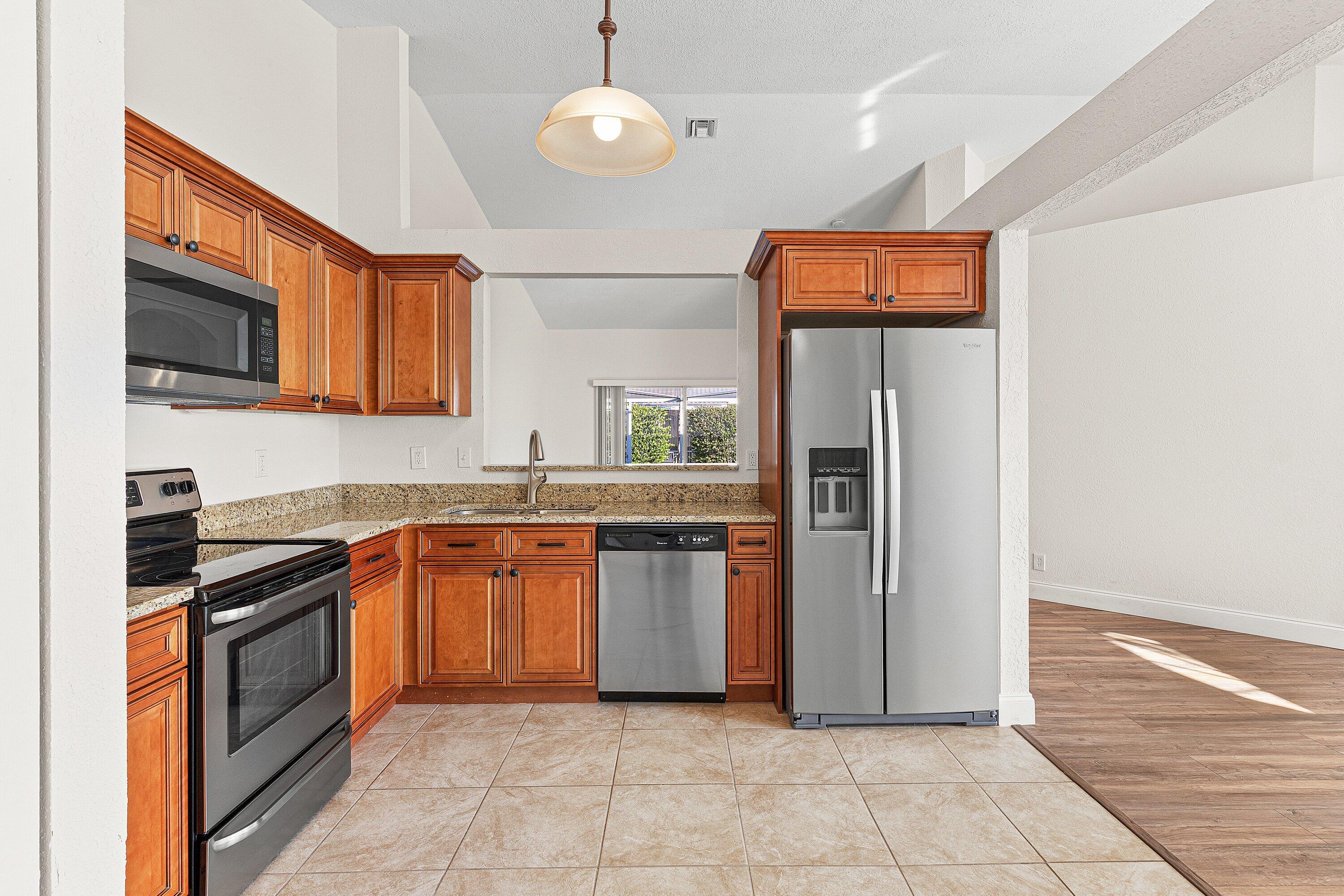 6081 Heliconia Road Delray Beach, FL 33484 - Photo 11 of 39 a kitchen with stainless steel appliances granite countertop a refrigerator and a stove top oven