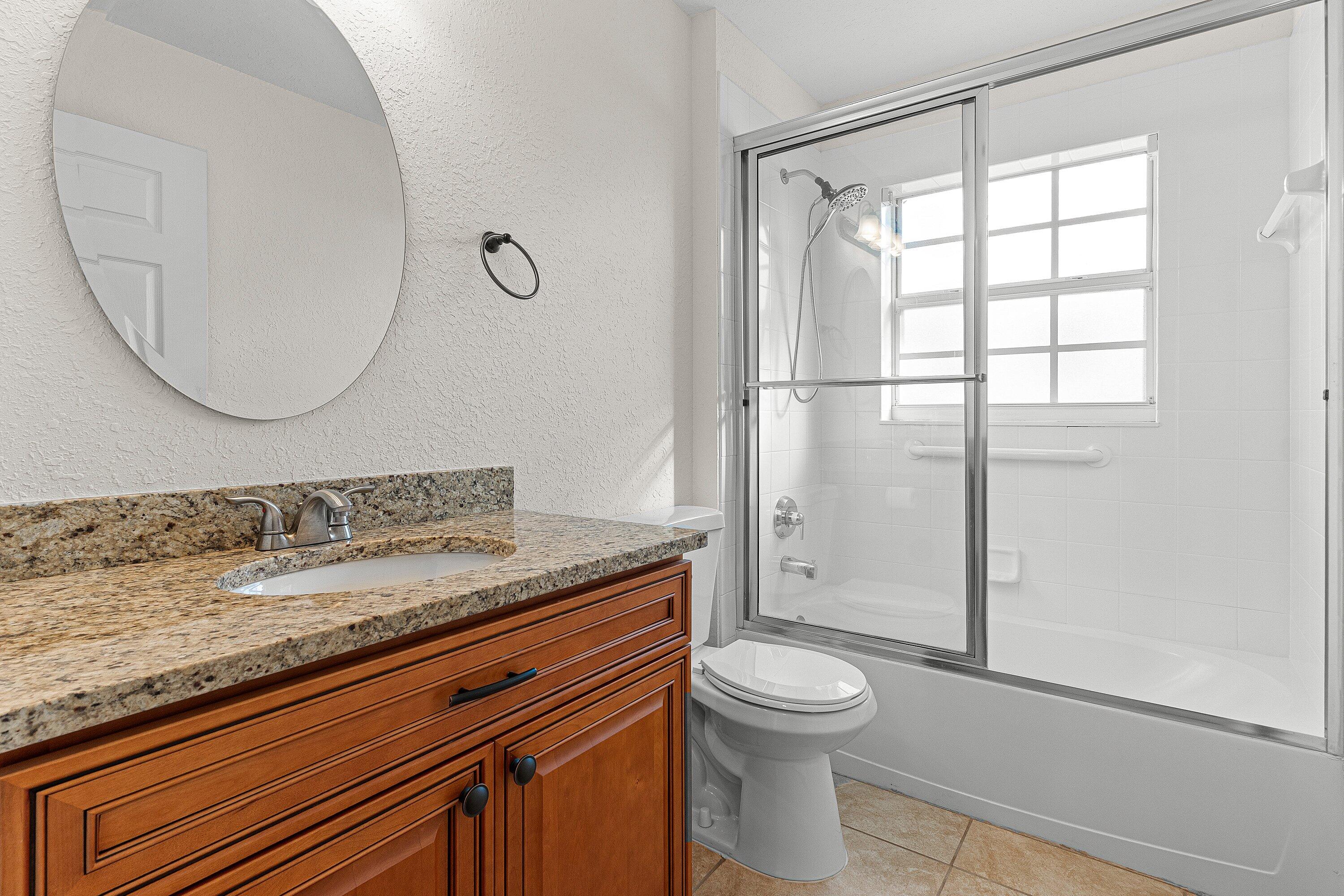 6081 Heliconia Road Delray Beach, FL 33484 - Photo 13 of 39 a bathroom with a granite countertop sink a toilet and shower