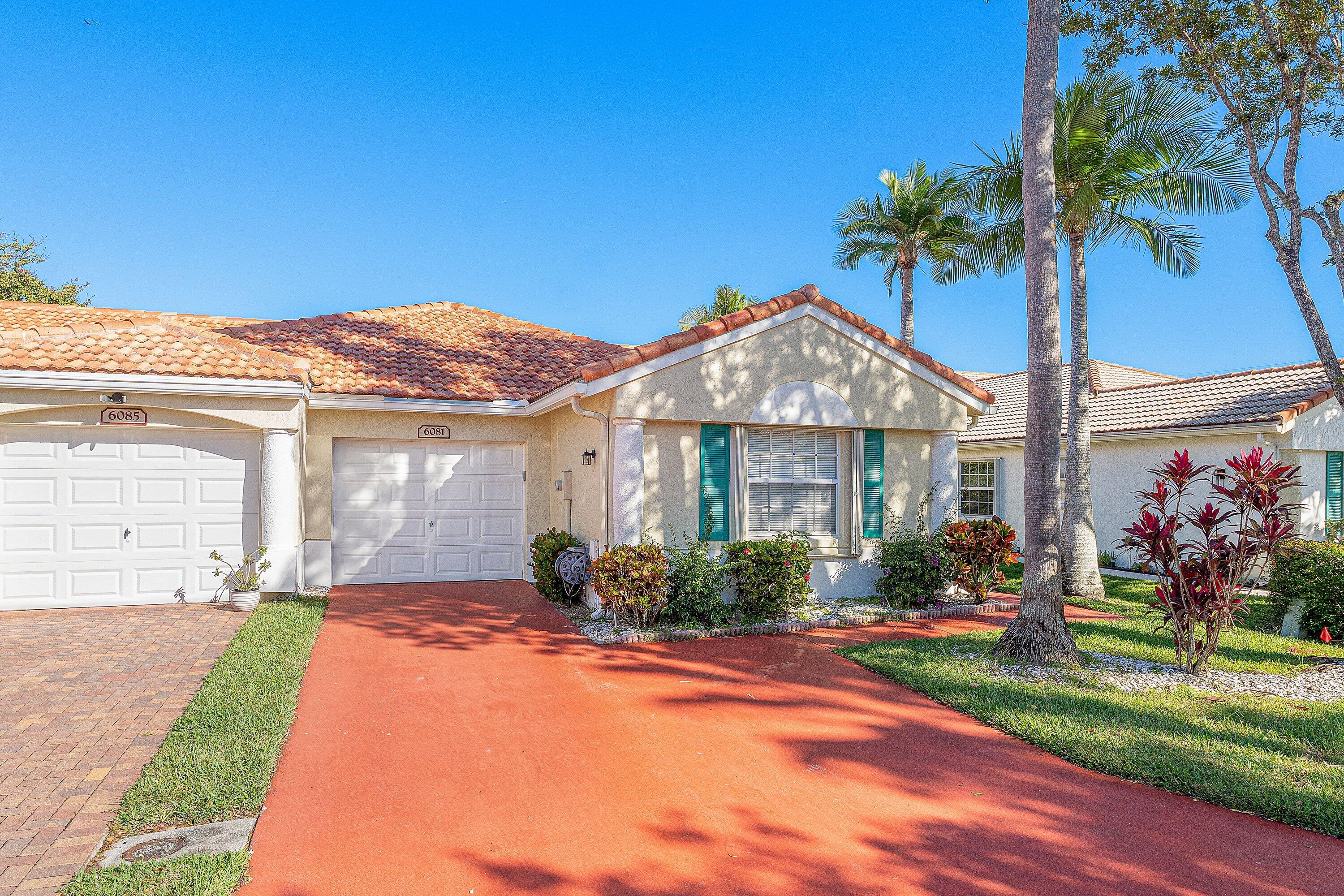 6081 Heliconia Road Delray Beach, FL 33484 - Photo 2 of 39 a front view of a house with a garden and yard