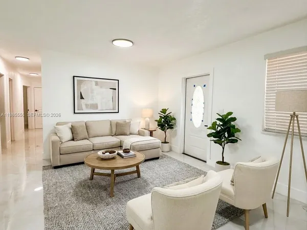 a living room with furniture a potted plant and a wooden floor
