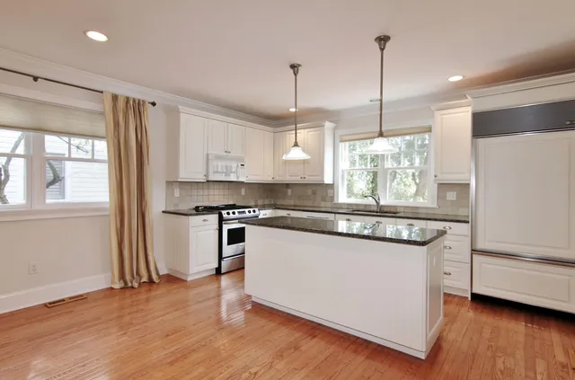 a kitchen with stainless steel appliances granite countertop a stove a refrigerator and a sink with wooden floors