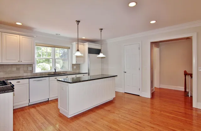 a kitchen with granite countertop wooden floors and white cabinets