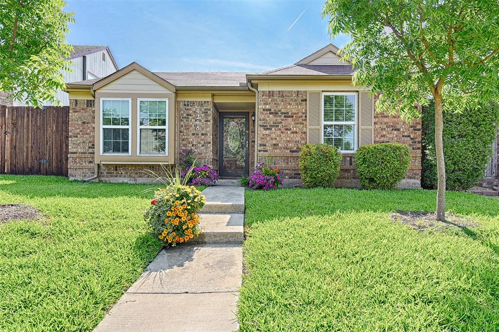 a front view of a house with a yard and potted plants