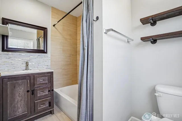 a bathroom with a sink a toilet and shower a mirror
