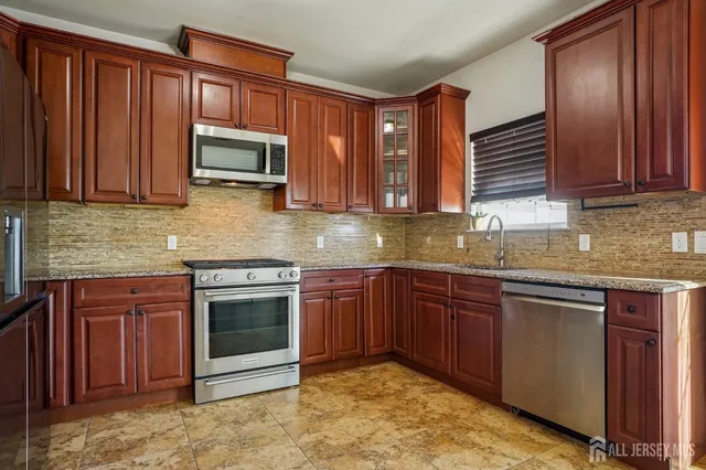 a kitchen with stainless steel appliances granite countertop wooden cabinets a stove top oven with granite countertops and cabinets