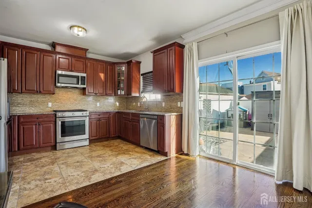 a kitchen with stainless steel appliances granite countertop a stove a sink dishwasher a refrigerator and a oven with wooden floor