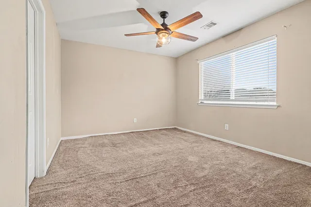 an empty room with a window and a fan