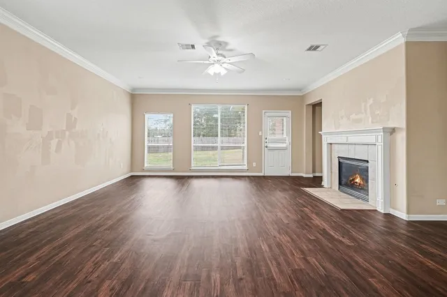 a view of an empty room with wooden floor and a fireplace