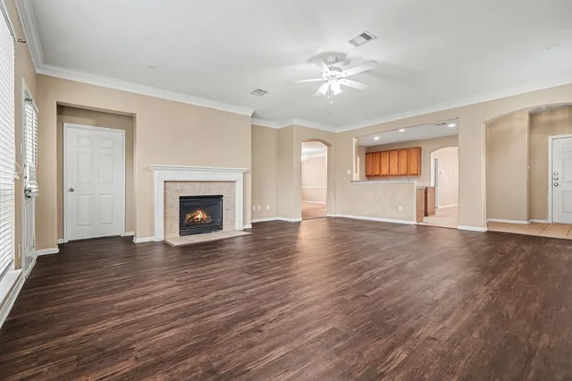 a view of an empty room with wooden floor and fireplace