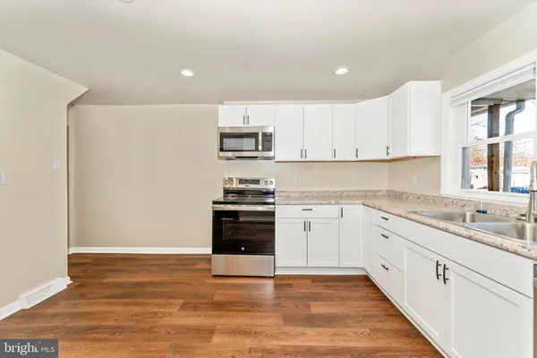a kitchen with granite countertop white cabinets and stainless steel appliances