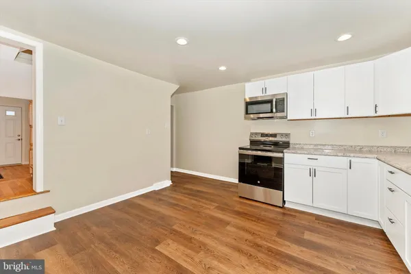 a kitchen with granite countertop white cabinets and stainless steel appliances