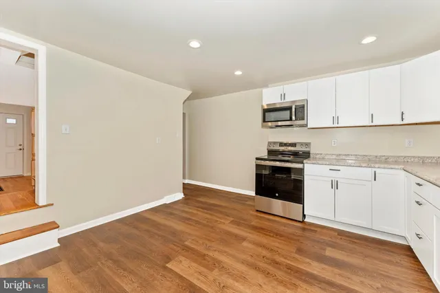 a kitchen with granite countertop white cabinets and stainless steel appliances