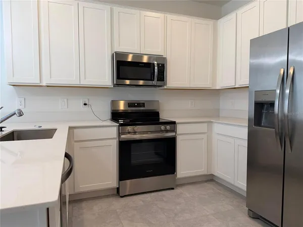 a kitchen with stainless steel appliances granite countertop a refrigerator stove and white cabinets