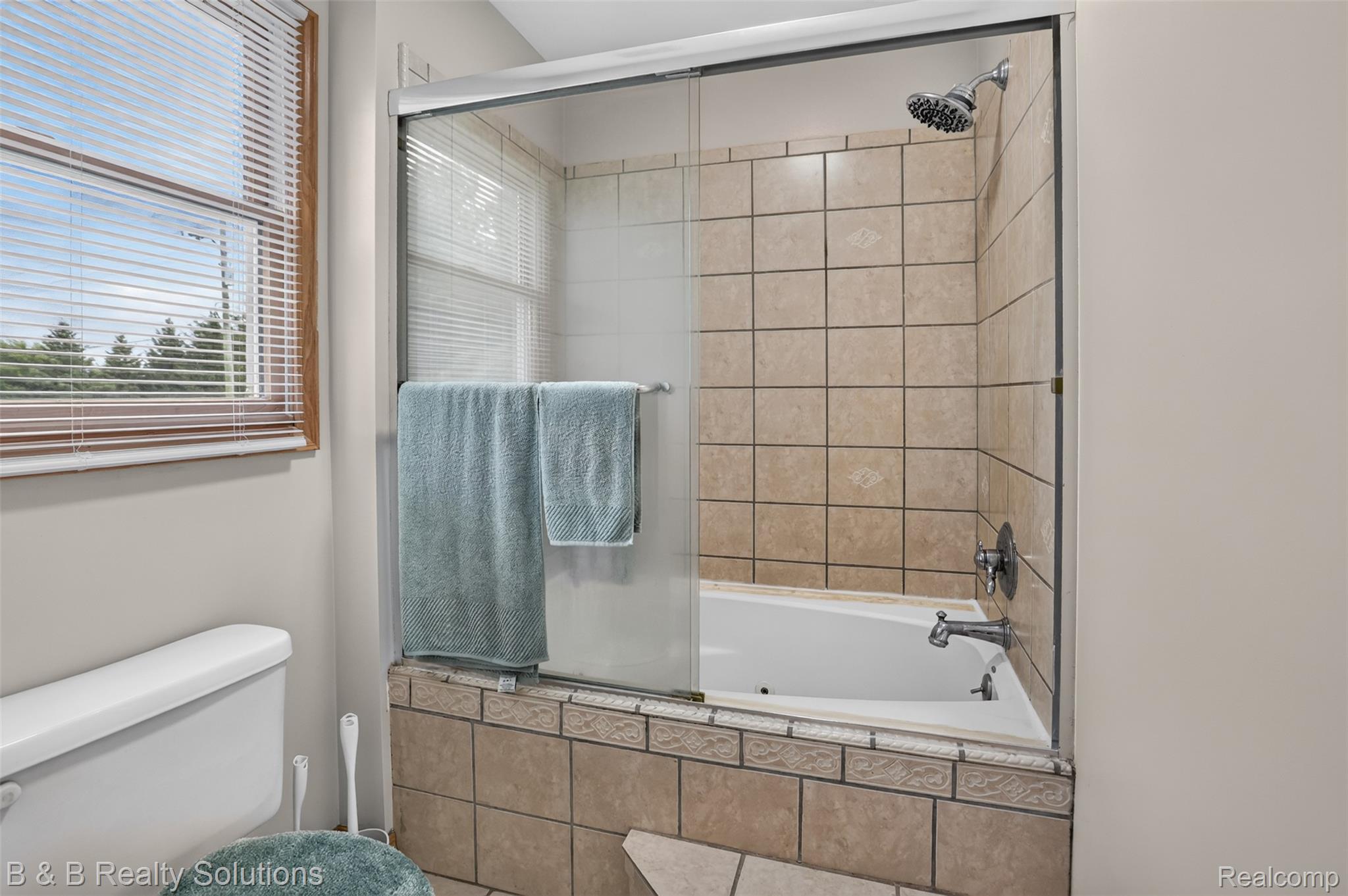 3097 East Burnside Road North Branch, MI 48461 - Photo 22 of 52 Bathroom featuring a combination shower and tub with sliding glass enclosure, light-toned wall tiling, and a window with wood-finish trim and horizontal blinds