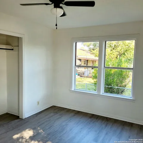 a view of an empty room with wooden floor and a window