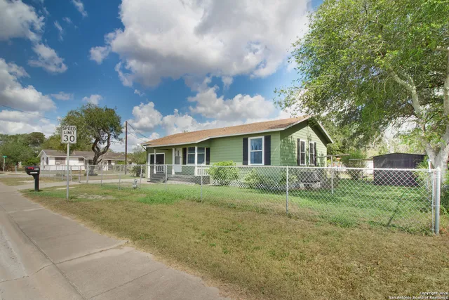 a view of house in front of a big yard with large trees
