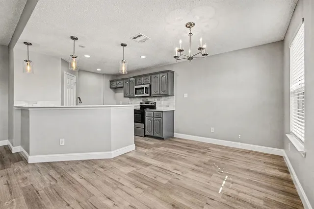 a large kitchen with granite countertop a stove a sink dishwasher a refrigerator and white cabinets with wooden floor