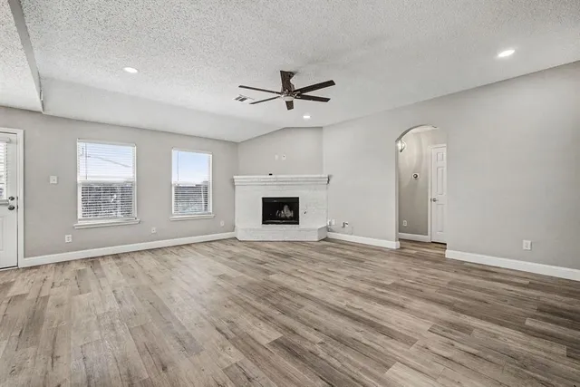 an empty room with wooden floor ceiling fan and windows