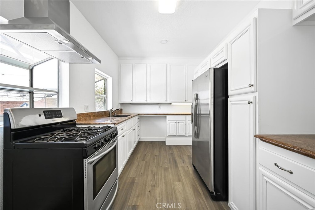a kitchen with stainless steel appliances a refrigerator a sink and white cabinets