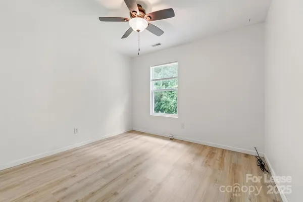 an empty room with a window and a fan