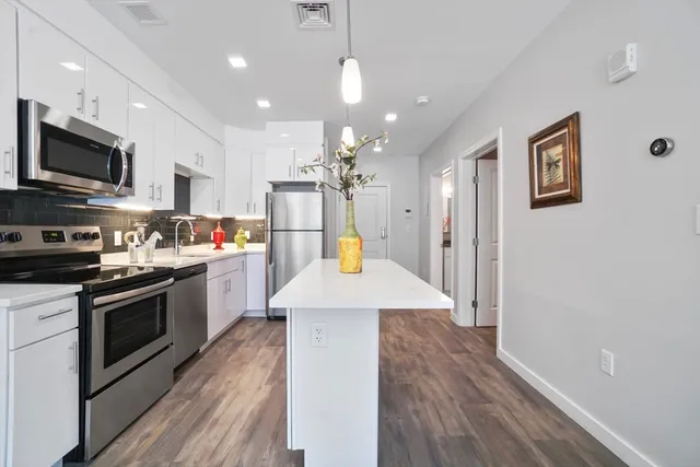 a kitchen with stainless steel appliances kitchen island granite countertop a stove a sink a refrigerator and a microwave