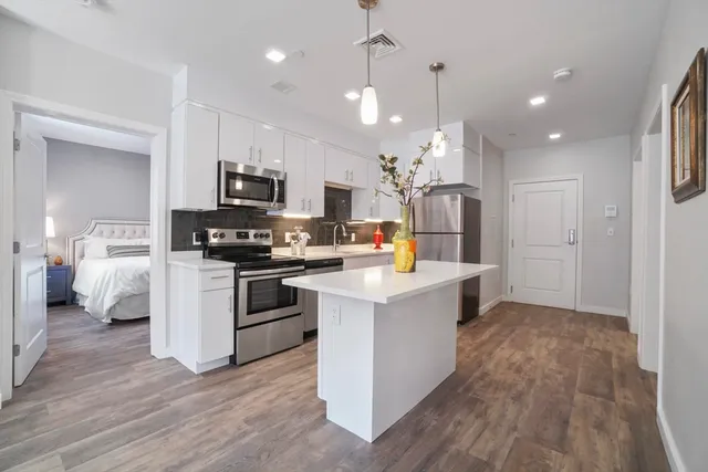 a kitchen with kitchen island white cabinets and stainless steel appliances