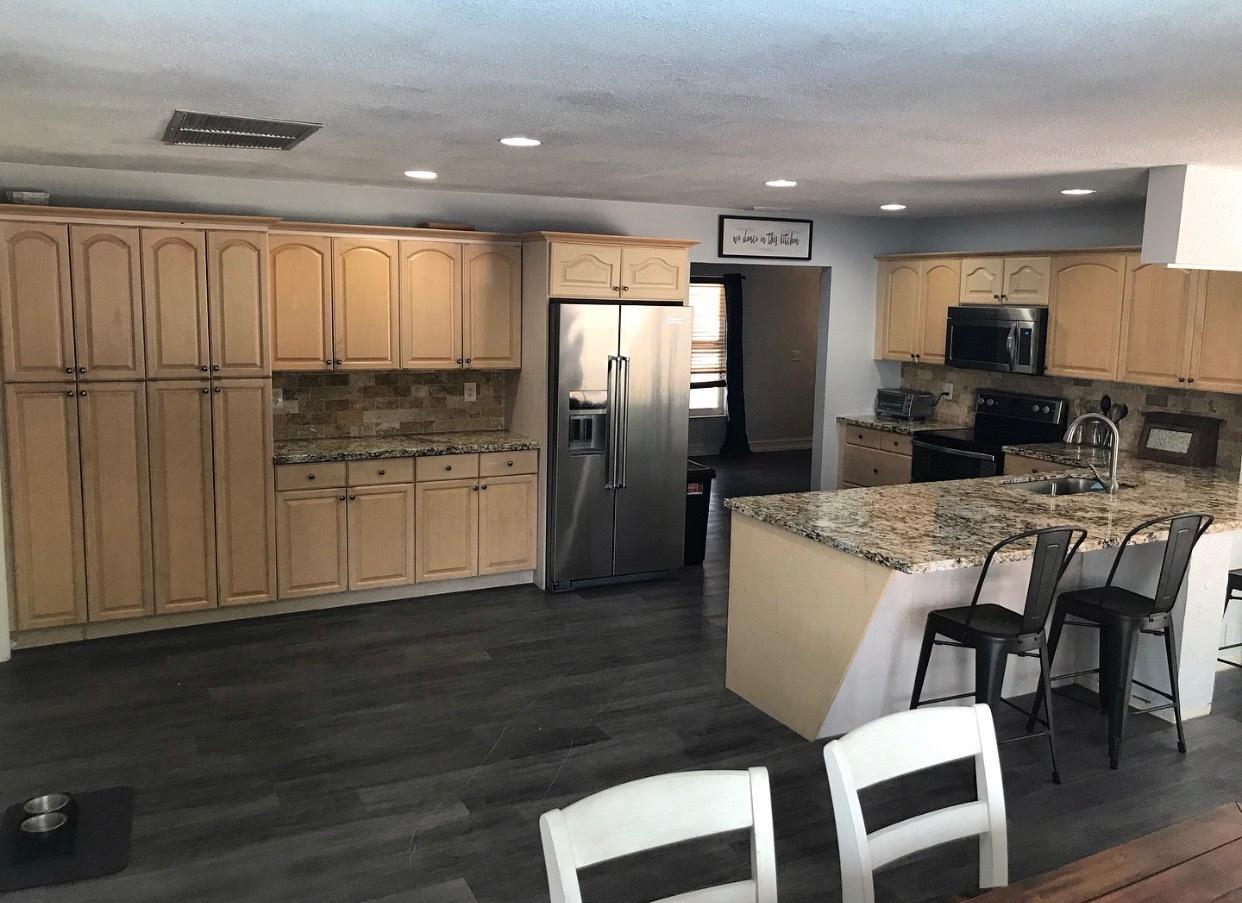 680 Southwest 17th Court Boca Raton, FL 33486 - Photo 4 of 27 a kitchen with stainless steel appliances kitchen island granite countertop a refrigerator a stove a microwave oven with white cabinets and wooden floor