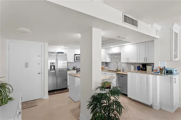 a kitchen with stainless steel appliances a refrigerator a sink a stove cabinets and a dining table