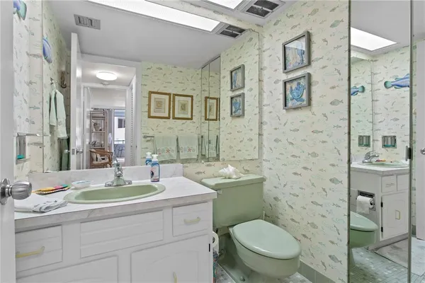 a bathroom with a toilet a sink a mirror a shower and vanity