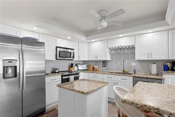 a kitchen with granite countertop a sink stainless steel appliances and white cabinets