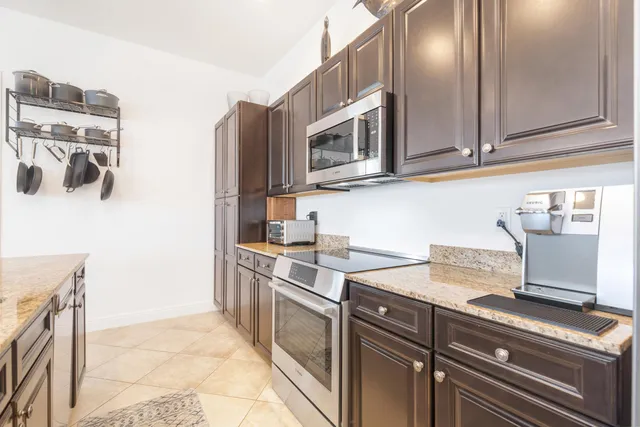 a kitchen with stainless steel appliances granite countertop a refrigerator a stove a sink a dining table and chairs