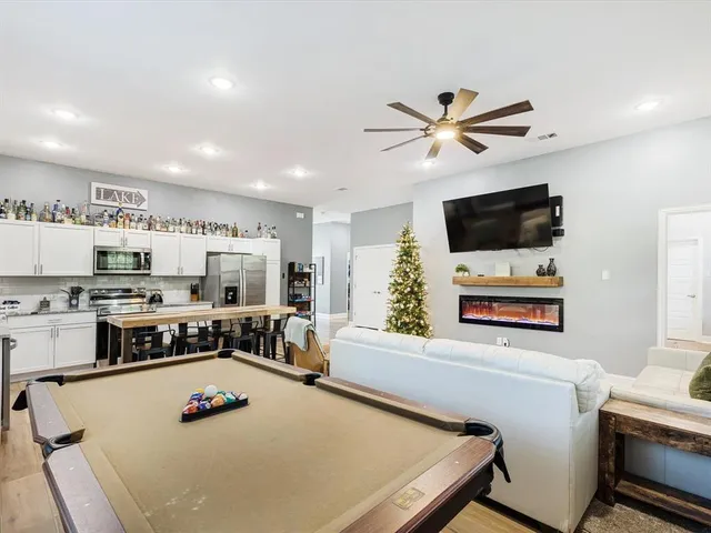 a living room with stainless steel appliances furniture and a flat screen tv