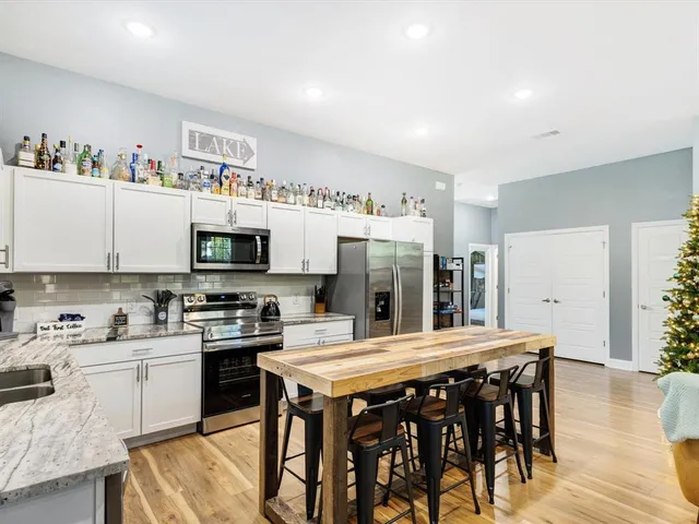 a kitchen with stainless steel appliances granite countertop a stove a sink dishwasher and white cabinets with wooden floor