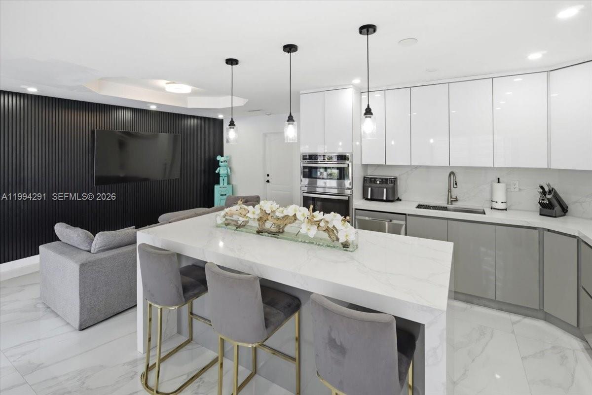 15763 Southwest 43rd Street Miami, FL 33185 - Photo 13 of 46 a kitchen with stainless steel appliances kitchen island granite countertop a table chairs in it and white cabinets