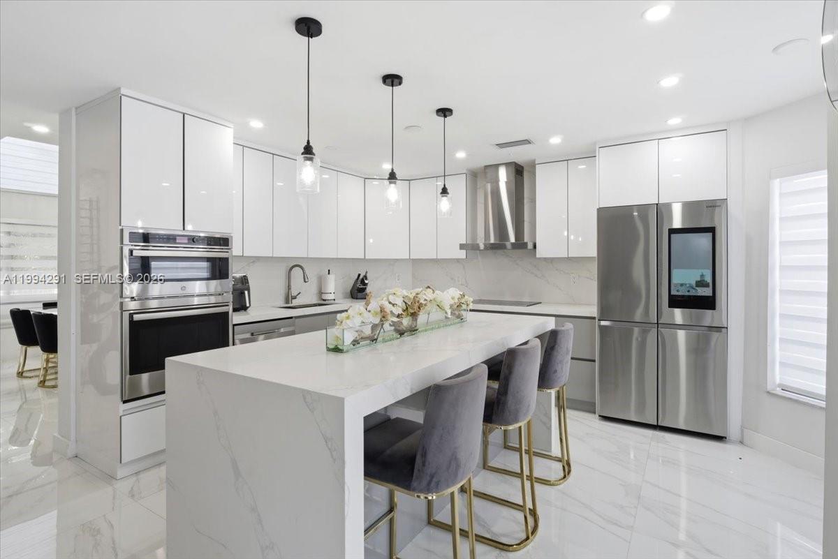 15763 Southwest 43rd Street Miami, FL 33185 - Photo 15 of 46 a kitchen with stainless steel appliances kitchen island a refrigerator and a stove top oven