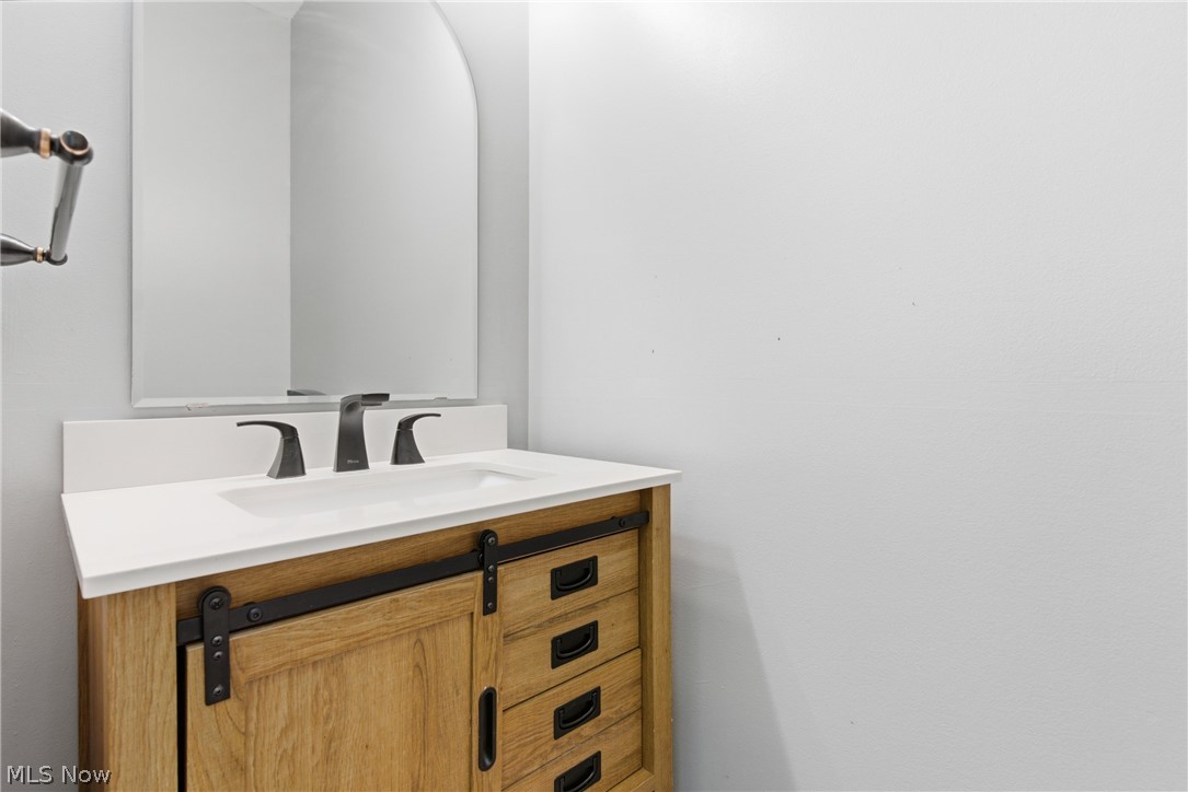11678 Dunham Road Northfield, OH 44067 - Photo 14 of 38 Modern vanity with a white countertop and integrated sink, featuring a barn door style cabinet front and matte black hardware