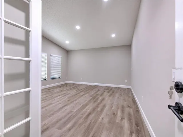 an empty room with wooden floor and windows