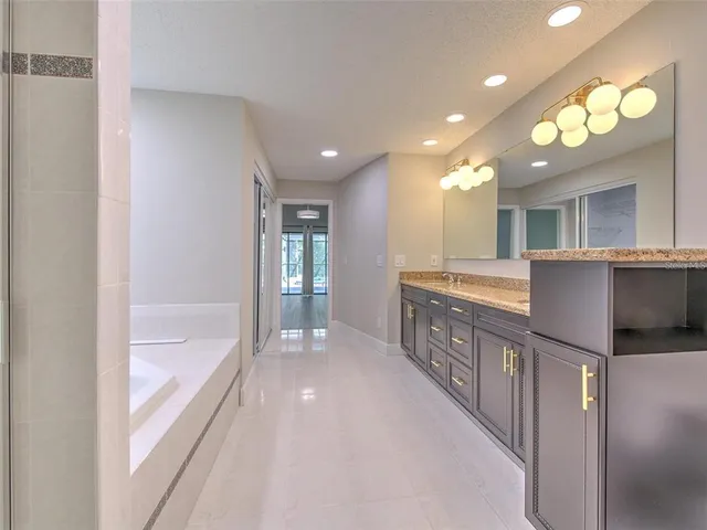 a bathroom with a granite countertop double vanity sink a toilet and a large mirror