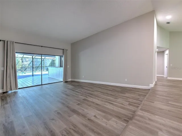 a large room with fireplace chandelier and wooden floor