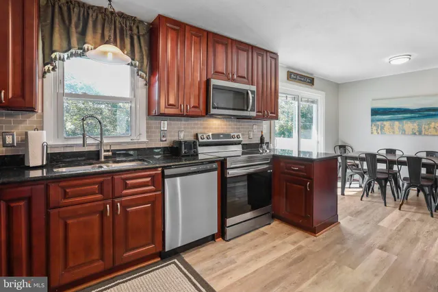 a kitchen with stainless steel appliances granite countertop wooden cabinets a stove a sink and a large window